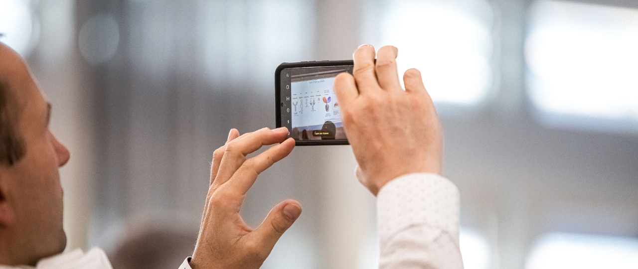 Teilnehmer fotografiert Präsentation mit seinem Handy