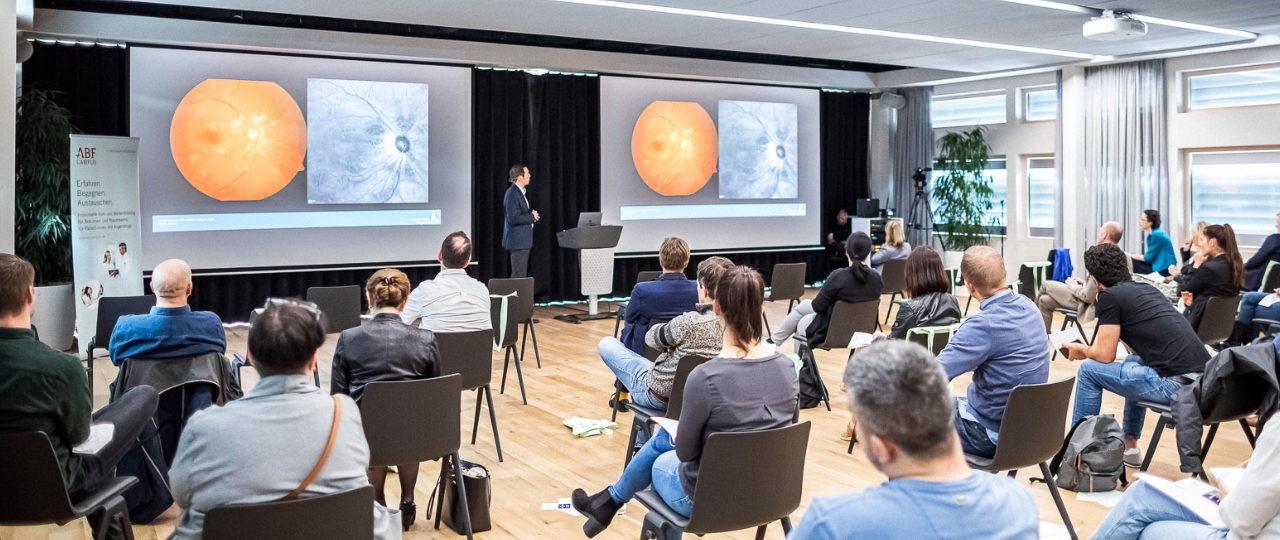 Personen sitzen in Konferenzraum und sehen eine Präsentation